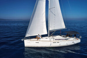 gallery-Incognito-5 | Sail in Greece™ Sailboat with white sails on calm blue sea, passengers relaxing on deck under clear sky.