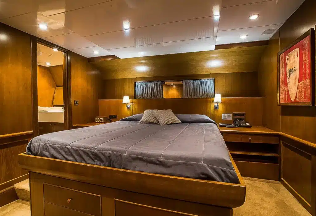 Wood-paneled hotel bedroom with a large bed, two wall lamps, and a red-framed abstract painting on the right.
